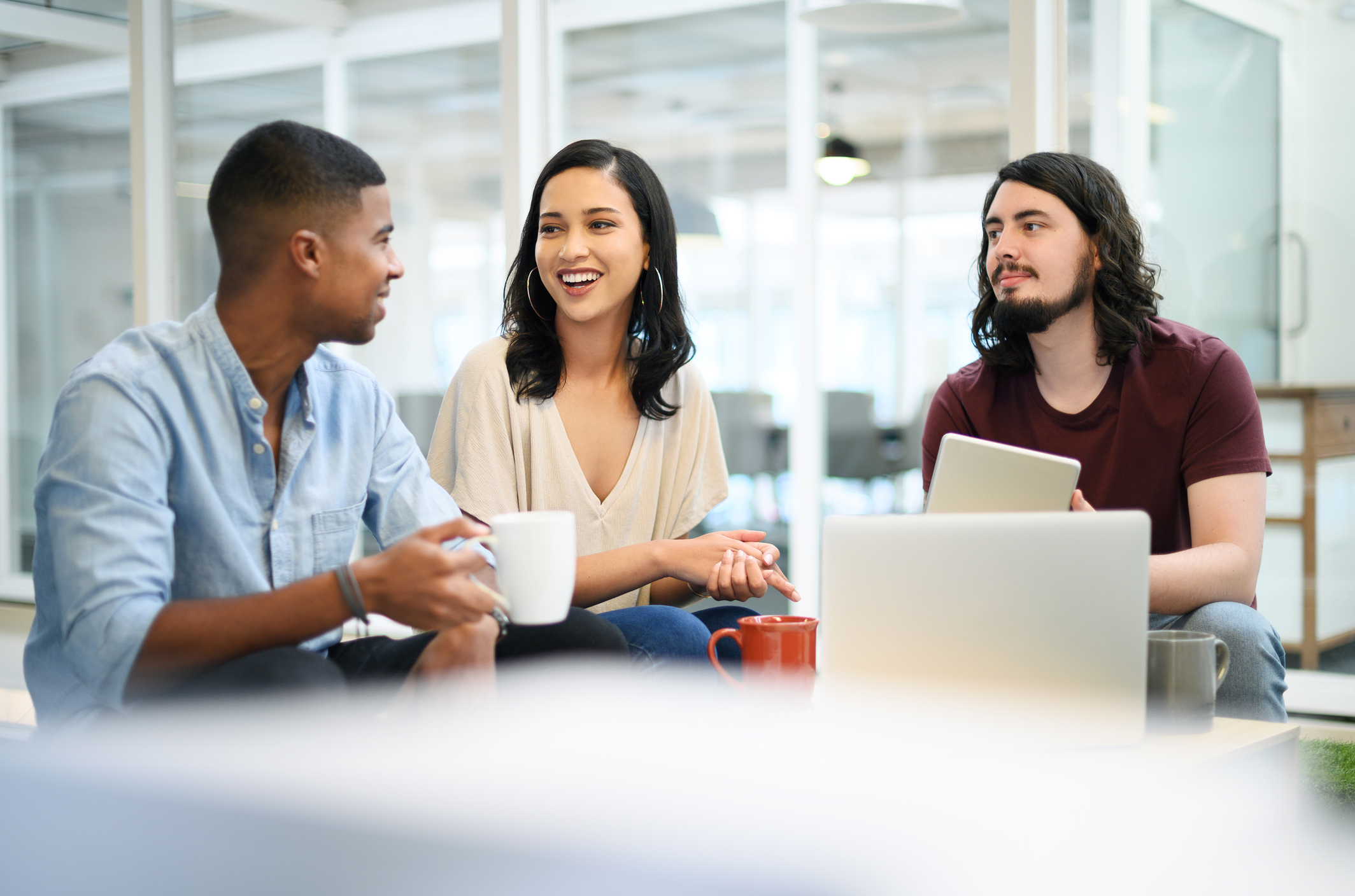 Three individuals sitting in office break room.